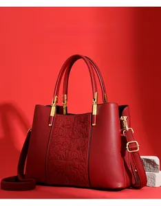 Detail of red bridal handbag with floral embroidery and golden hardware accents
