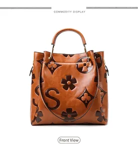 Detailed close-up of brown embossed faux leather tote bag with classic pattern and round handles