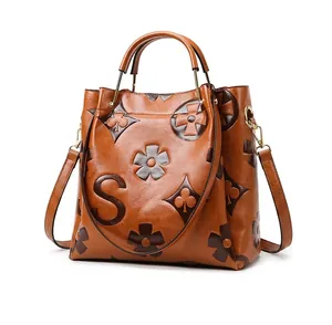 Detail view of caramel brown tote bag with embossed pattern and golden hardware