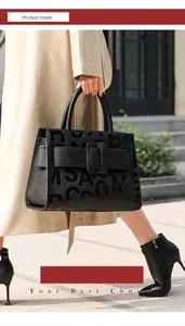 Detail of black tote bag featuring pebble grain leather and embossed letter texture
