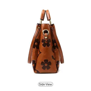 Side view detail of a large brown leather tote bag with floral print and gold metal rings