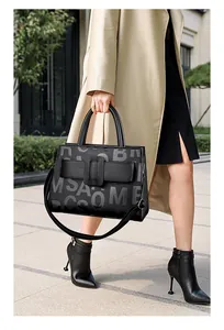 Detail of black pebbled leather tote bag featuring letter print and large buckle design