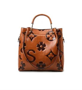 Rear view of brown embossed leather tote bag with gold hardware and logo detail