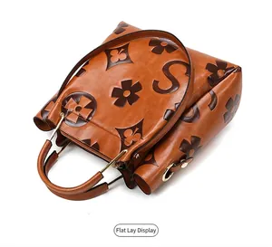 Detailed view of caramel embossed leather bucket bag featuring star and clover patterns