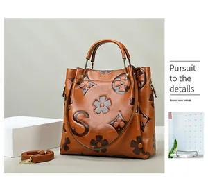 Macro shot of brown leather bucket bag showing floral embossing and metal handle detail