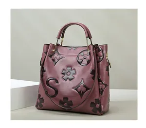 Close-up of embossed floral motifs and a large letter S on a burgundy leather tote bag