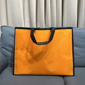 Bolsa de regalo minimalista naranja de alta calidad con bordes negros en sofá azul