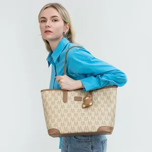 Detail of canvas tote bag with monogram print and brown leather shoulder strap