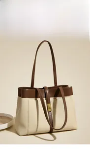 Detail of canvas tote bag with brown leather trim and golden twist-lock closure