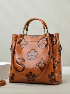 Brown litchi texture bucket bag with vintage pattern and gold hardware on white pedestal
