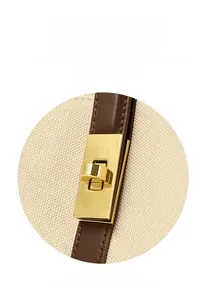 Detailed shot of golden metal twist lock on beige canvas and brown leather tote bag