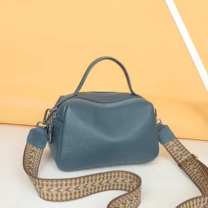 Detail view of leather satchel showing litchi texture and patterned woven strap