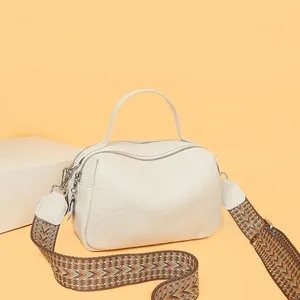 Detail of genuine leather pillow bag with dual zippers and colorful woven wide strap