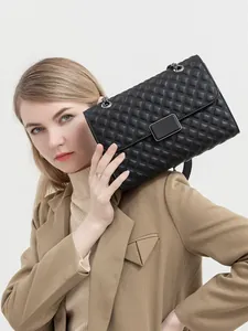 Detalle de bolso bandolera acolchado negro con cadena metálica y cierre rectangular moderno