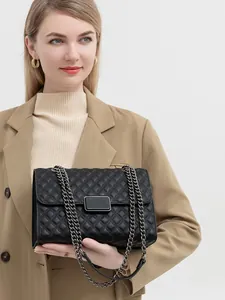 Detalle de bolso acolchado negro con cadena de metal oscuro y cierre metálico elegante