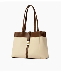 Side view detail of canvas tote bag with brown leather straps and gold metal clasp