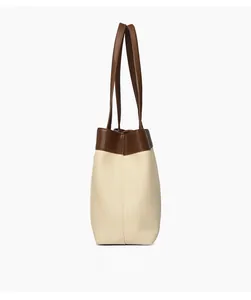 Side view of large canvas tote bag showing contrast brown leather trim and stitching
