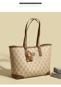 Detail of printed tote bag with M-pattern fabric and brown leather handle and duck charm