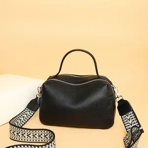 Black leather crossbody pillow bag with lychee texture and wide woven shoulder strap