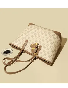Detail of beige tote bag with brown W jacquard pattern and leather bear charm accessory