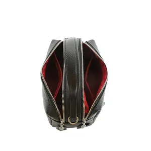 Black pebbled leather crossbody pillow bag with dual zippers and red fabric lining