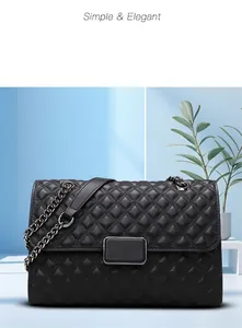 Detalle de bolso bandolera en piel acolchada negra con cadena y hebilla de metal dorado