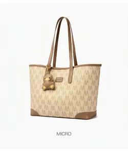 Detail view of large beige tote bag with brown handles and repeated M-pattern texture