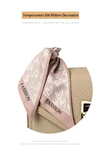 Detail einer beigen Lederhandtasche mit goldenem Schloss und Mode-Herz-Schleife