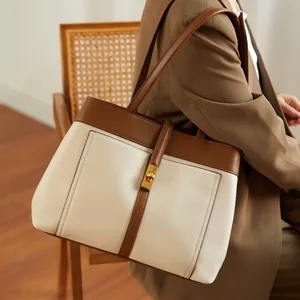 Detail of minimalist cream canvas tote bag with brown trim and golden twist lock closure