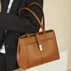 Close-up of brown leather tote bag featuring gold lock and stitching details on strap