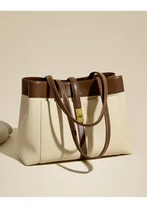 Detail view of large canvas tote bag with brown leather trim and golden metal swivel lock