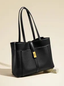Minimalist black canvas tote bag with leather straps and gold metal twist lock buckle