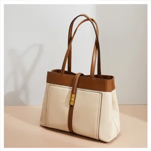 Detail of minimalist cream and brown tote bag showing gold metal twist lock and stitching