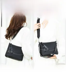 Detail of leather crossbody bag showing two interchangeable straps for versatile carrying