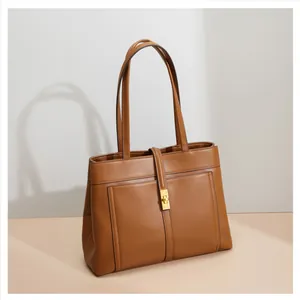 Detail of caramel brown tote bag with smooth texture and golden metal square buckle