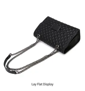 Vista de cerca de bolso bandolera acolchado negro con cadena plateada y hebilla cuadrada