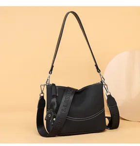 Detail of black lychee leather crossbody bag with silver hardware and fashion strap