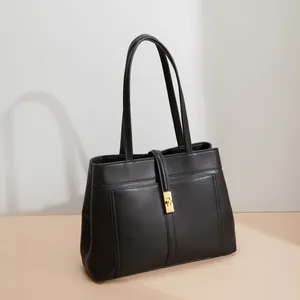 Detail of black matte leather tote bag featuring elegant golden twist lock and long strap
