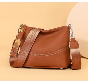 Macro detail of brown pebble leather texture and wide strap with embroidered text