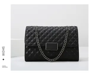 Detalle de bolso de hombro acolchado en cuero negro con cadena y cierre metálico