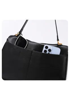 Detail van de achterzakken van de zwarte leren tas met smartphone en een zonnebril erin
