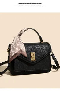 Details der schwarzen Lederhandtasche mit goldenem Drehverschluss und Seidenschal-Deko