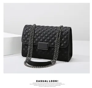 Detalle de bolso acolchado negro con correa de cadena plateada y cierre de metal