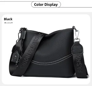 Detail of black leather shoulder bag with white contrast stitching and logo strap