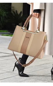 Detail of elegant beige leather tote with vertical brown stripes and golden metal hardware