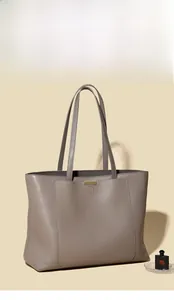Detail of grey leather tote bag showing high-quality pebbled texture and gold ornament