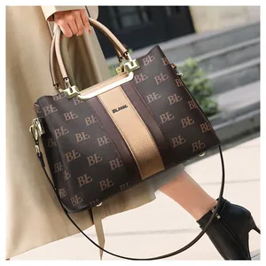 Detail of a large brown and gold tote bag with logo pattern shown on a female model