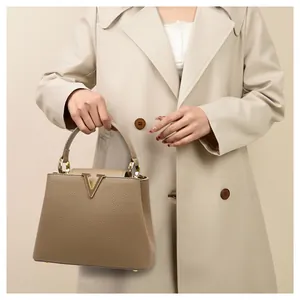 Detail of khaki leather bucket bag with gold V logo shown on beige trench coat outfit