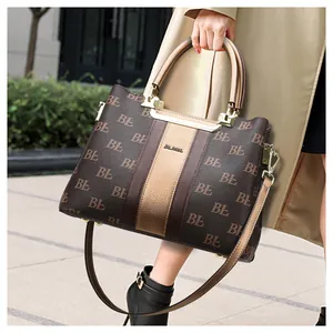 Close-up of structured monogram tote bag with golden hardware and leather strap detail