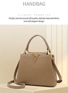 Detailed close-up of brown pebbled leather tote with golden V-shaped metal logo and handle